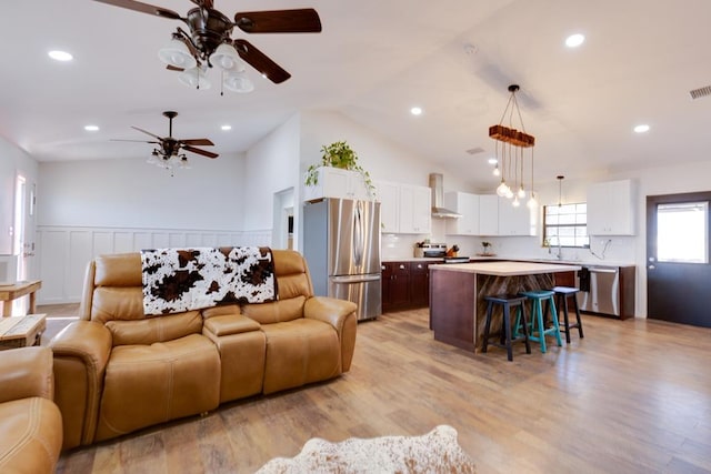 living room with lofted ceiling, sink, ceiling fan, and light wood-type flooring