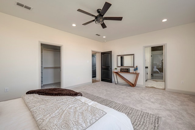 bedroom featuring a walk in closet, ceiling fan, a closet, and light carpet