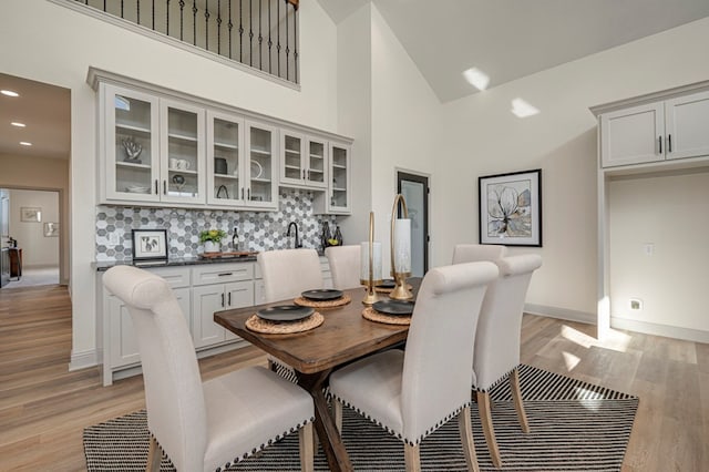 dining room with light hardwood / wood-style floors and high vaulted ceiling