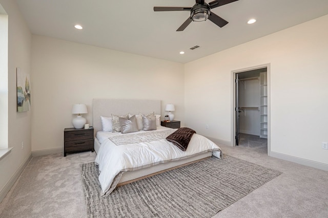 carpeted bedroom with a walk in closet, a closet, and ceiling fan