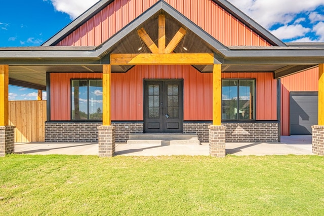 view of exterior entry with a lawn, french doors, and covered porch