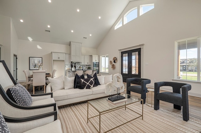 living room featuring french doors, high vaulted ceiling, and light hardwood / wood-style floors