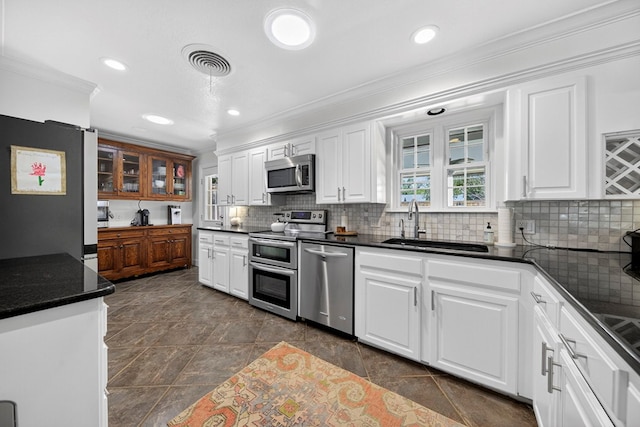 1602 Cimmaron Dr, Midland, TX 79705 - kitchen with appliances with stainless steel finishes, crown molding, dark countertops, white cabinetry, and backsplash