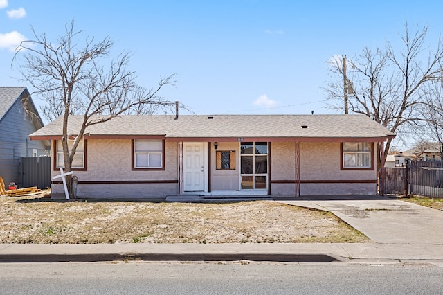 single story home featuring stucco siding, a shingled roof, and fence