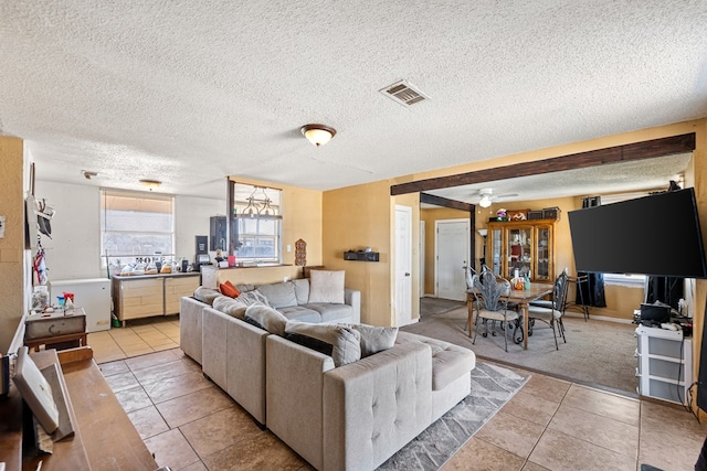 carpeted living room featuring tile patterned flooring, ceiling fan, visible vents, and a textured ceiling