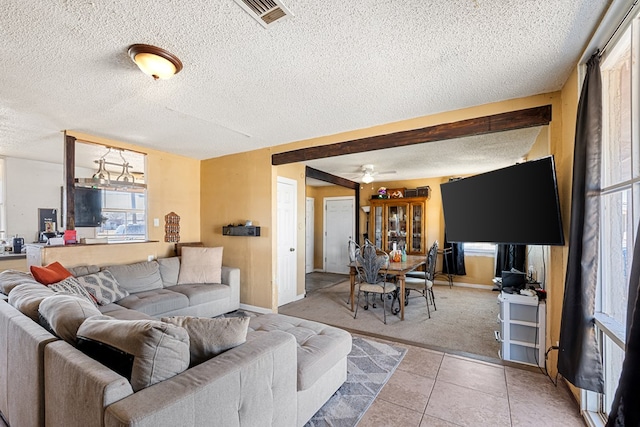 living room featuring visible vents, a textured ceiling, light tile patterned flooring, baseboards, and ceiling fan