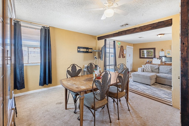 carpeted dining room featuring visible vents, ceiling fan, baseboards, beamed ceiling, and a textured ceiling