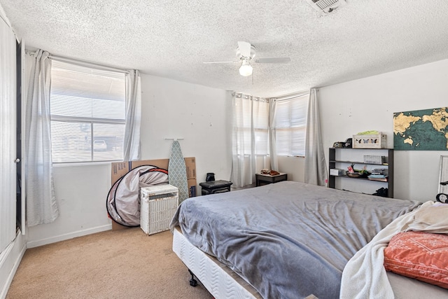 carpeted bedroom featuring baseboards, visible vents, a textured ceiling, and ceiling fan