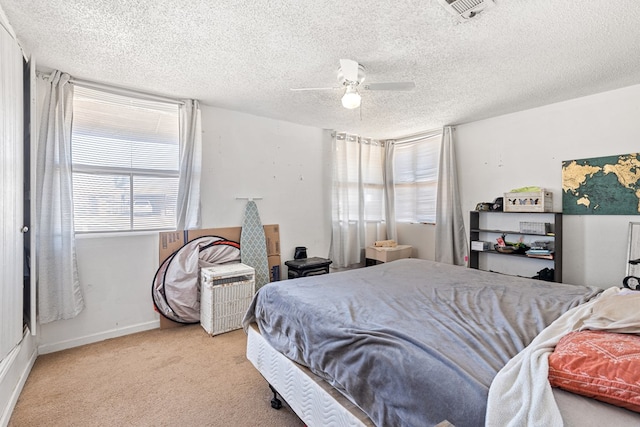 carpeted bedroom featuring visible vents, baseboards, a textured ceiling, and a ceiling fan