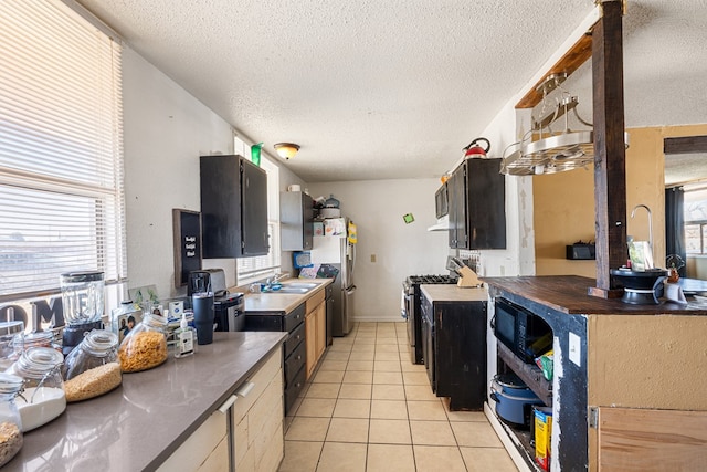 kitchen featuring light tile patterned floors, stainless steel appliances, a textured ceiling, and a sink