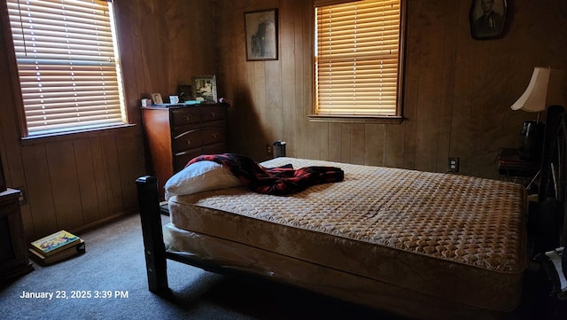 carpeted bedroom featuring wood walls