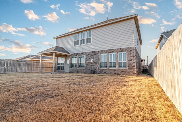 back of house featuring central air condition unit, a fenced backyard, a lawn, and brick siding