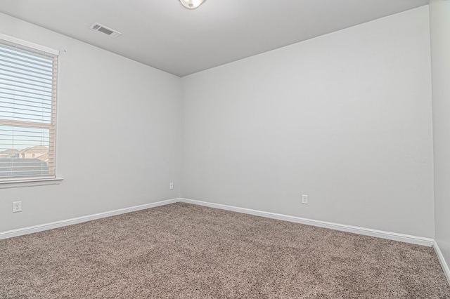 unfurnished room featuring carpet floors, visible vents, and baseboards