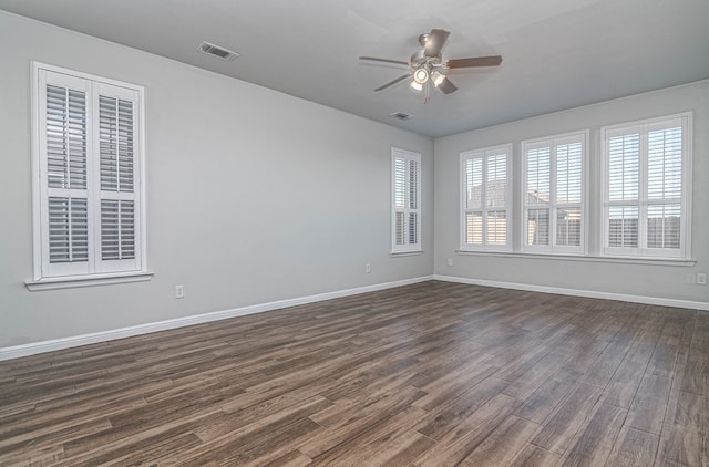 unfurnished room with dark wood-style flooring, visible vents, ceiling fan, and baseboards