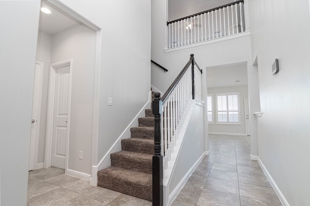 staircase with a towering ceiling and baseboards