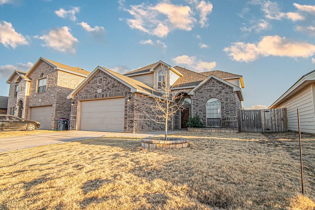 view of front of property with driveway, brick siding, an attached garage, and fence