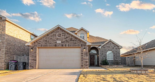 view of front of property featuring brick siding, a shingled roof, an attached garage, fence, and driveway