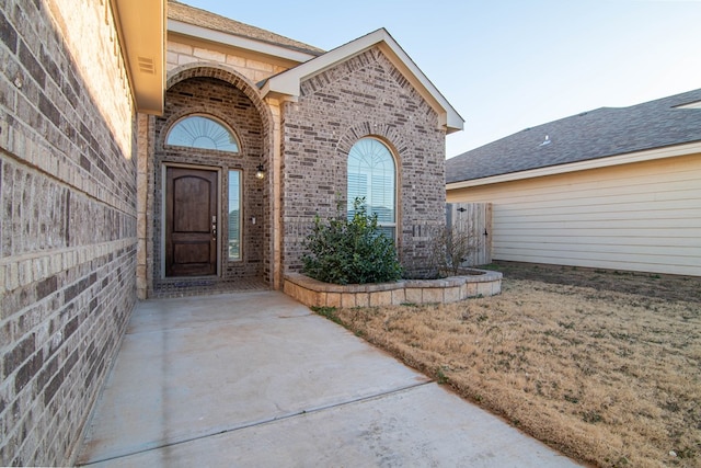 doorway to property with a yard and brick siding