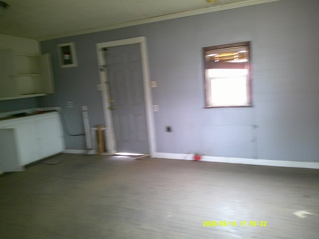 1100 Nolan St, Big Spring, TX 79720 - kitchen featuring crown molding, baseboards, wood finished floors, and white cabinetry