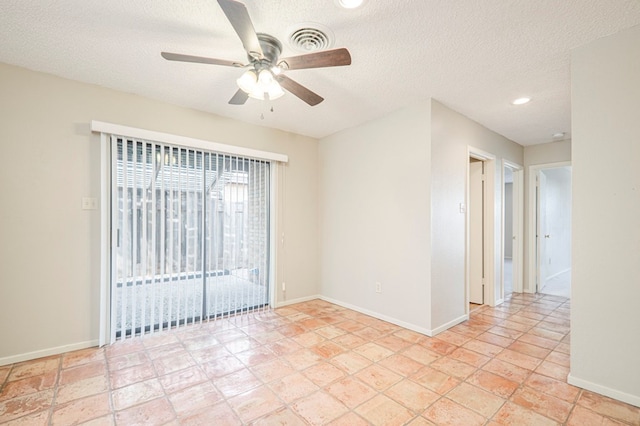 spare room featuring a textured ceiling, a ceiling fan, visible vents, and baseboards