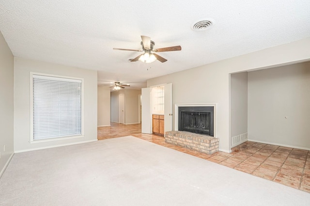 unfurnished living room featuring ceiling fan, a textured ceiling, a fireplace, and visible vents