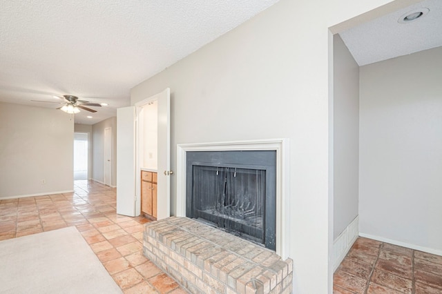 living room with a fireplace with raised hearth, ceiling fan, a textured ceiling, and baseboards