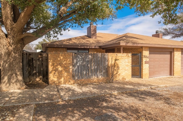 view of front of house with brick siding, fence, a chimney, and an attached garage