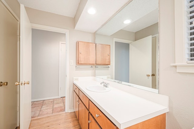 bathroom featuring wood finished floors, vanity, baseboards, and a textured ceiling