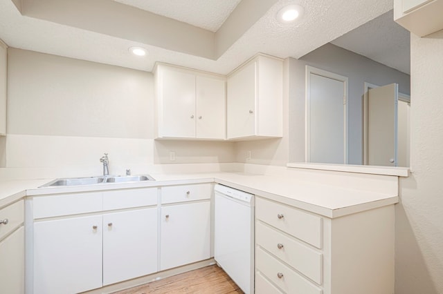 kitchen with white cabinets, light countertops, dishwasher, and a sink