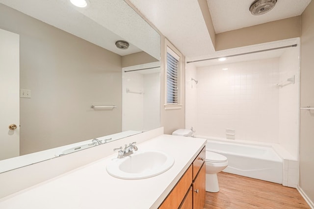 full bathroom featuring a textured ceiling, toilet, wood finished floors, vanity, and shower / washtub combination