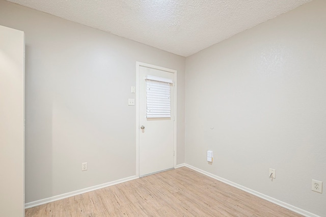 unfurnished room featuring light wood-type flooring, a textured ceiling, and baseboards