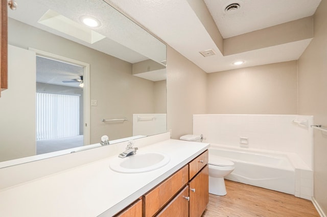 full bathroom featuring toilet, wood finished floors, visible vents, vanity, and a bath