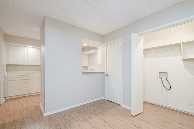 laundry area with a textured ceiling, hookup for a washing machine, laundry area, baseboards, and light wood-style floors