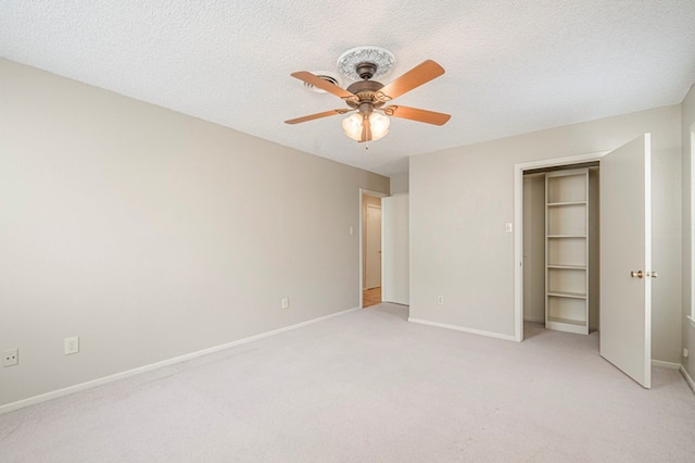 unfurnished bedroom featuring a textured ceiling, ceiling fan, light carpet, and baseboards