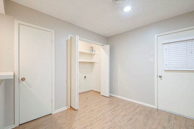 interior space with light wood-type flooring, a textured ceiling, and baseboards