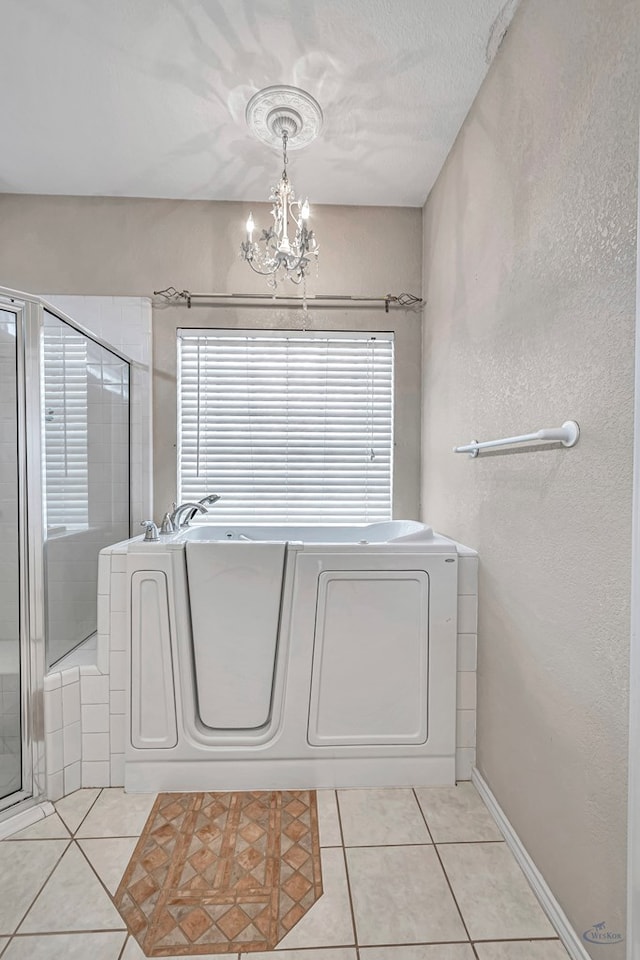 bathroom featuring washing machine and clothes dryer, tile patterned flooring, a shower with shower door, and an inviting chandelier