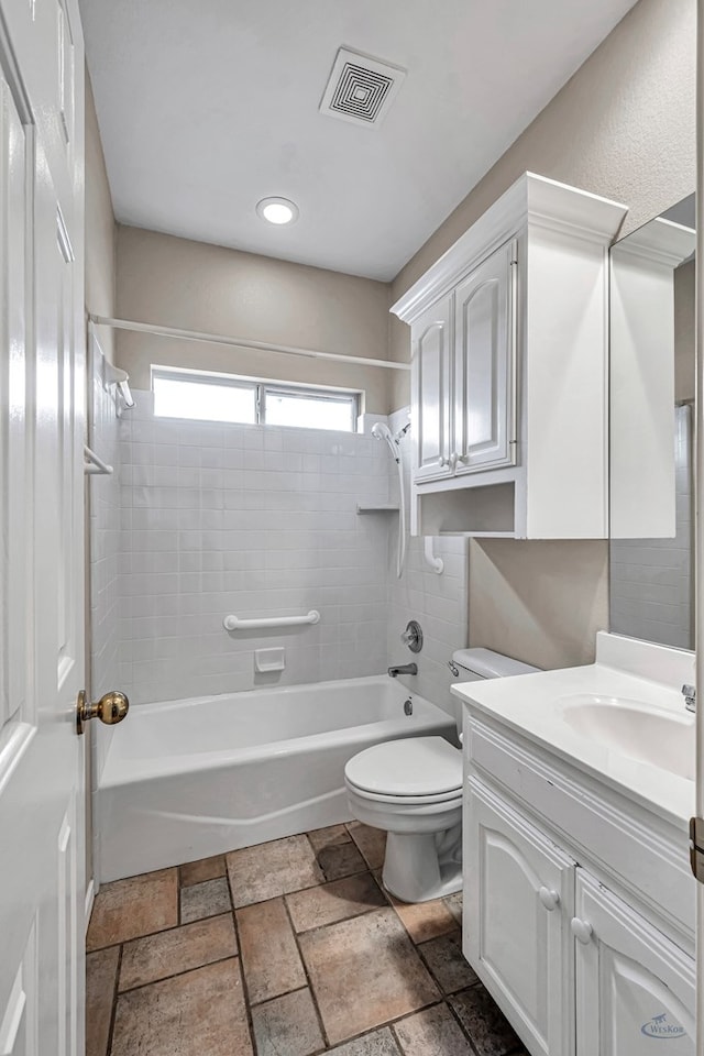 full bathroom with visible vents, toilet,  shower combination, stone tile flooring, and vanity