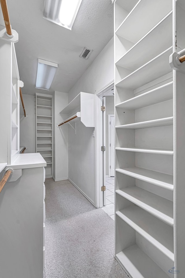 walk in closet featuring light carpet and visible vents