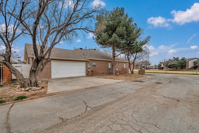 exterior space with an attached garage, concrete driveway, and brick siding