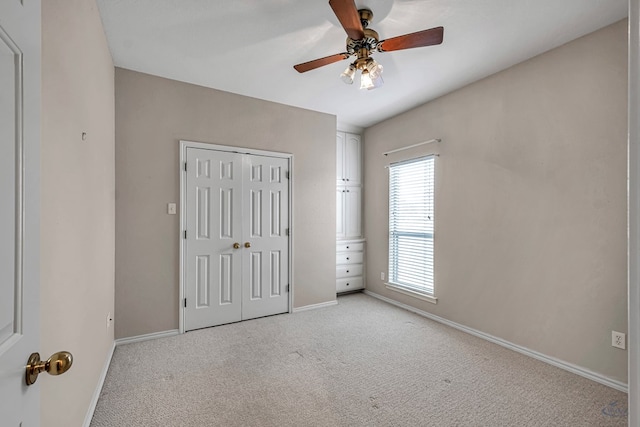 unfurnished bedroom with a ceiling fan, baseboards, a closet, and light colored carpet