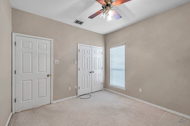 unfurnished bedroom with a closet, visible vents, light carpet, and baseboards