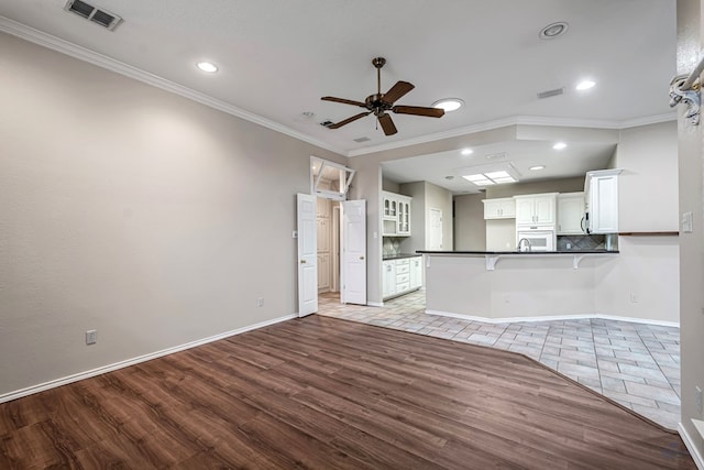 kitchen featuring a peninsula, visible vents, white cabinetry, dark countertops, and crown molding