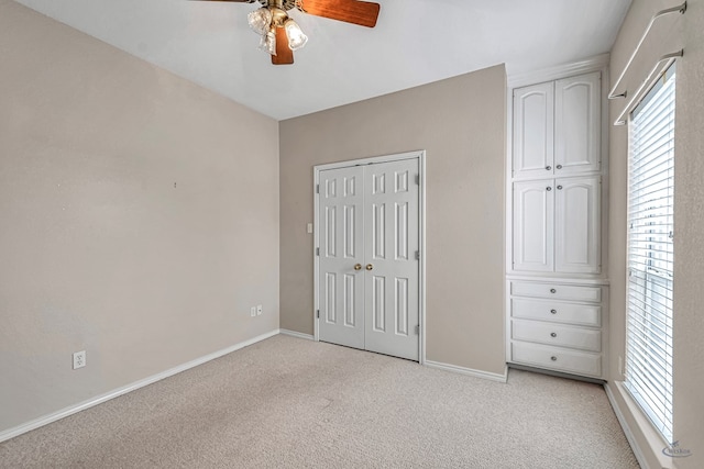 unfurnished bedroom featuring light carpet, multiple windows, and baseboards