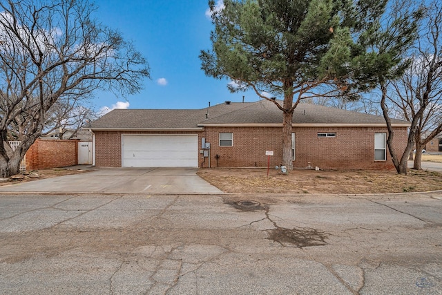 view of side of home with an attached garage, driveway, fence, and brick siding