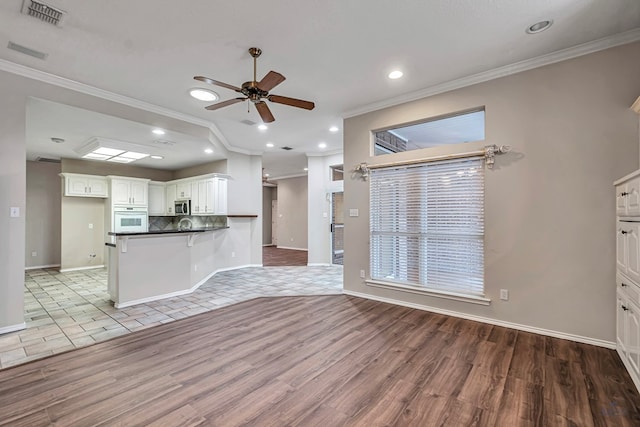 kitchen featuring visible vents, white cabinetry, white oven, stainless steel microwave, and dark countertops