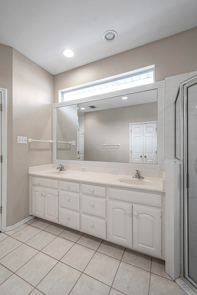 full bath with double vanity, a stall shower, a sink, and tile patterned floors