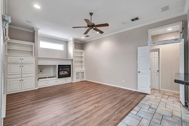 unfurnished living room featuring baseboards, a glass covered fireplace, visible vents, and light wood-style floors