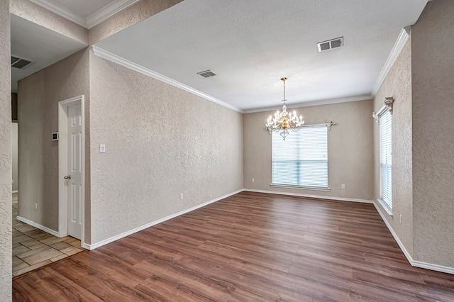 empty room featuring visible vents, wood finished floors, and a textured wall