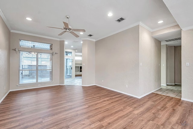 unfurnished room with light wood-style floors, baseboards, visible vents, and crown molding