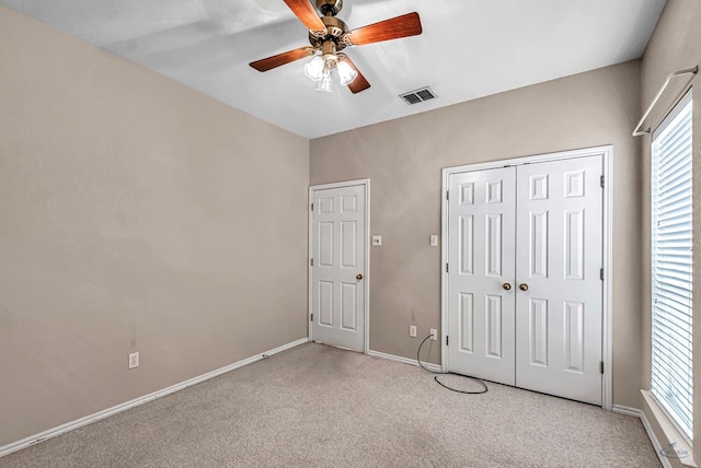 unfurnished bedroom featuring baseboards, visible vents, a ceiling fan, light colored carpet, and a closet